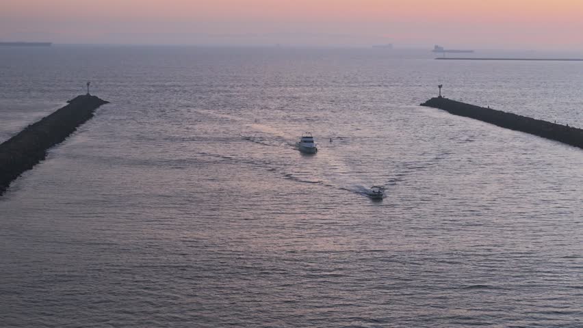Telephoto aerial shot of boats sailing through the Alamitos Bay Inlet at sunset, Seal Beach, California