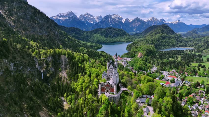 Stunning aerial footage of Neuschwanstein Castle in Bavaria, Germany, captured by drone. The iconic fairytale castle surrounded by mountains, forests, and dramatic landscape. Perfect example of 19th-c