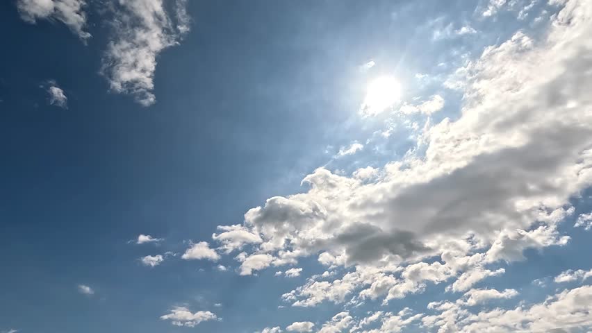 Fast flowing Clouds in the Daylight Skies. 4K video (Ultra High Definition) of cloudscape and bright sun. Sky and clouds Timelapse. Sun shines through the clouds on the blue sky background.