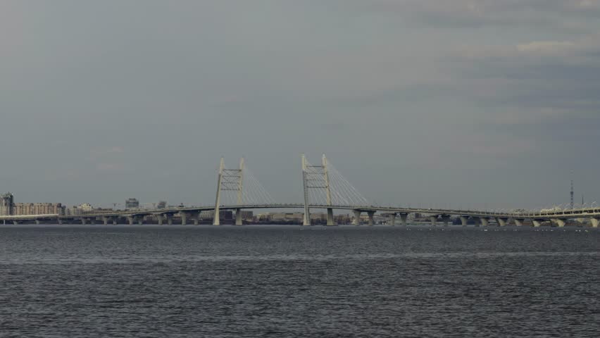 A wide, distant shot captures the impressive cable-stayed section of the Western High-Speed Diameter (WHSD) bridge, stretching across the Neva Bay in Saint Petersburg, Russia. The modern bridge