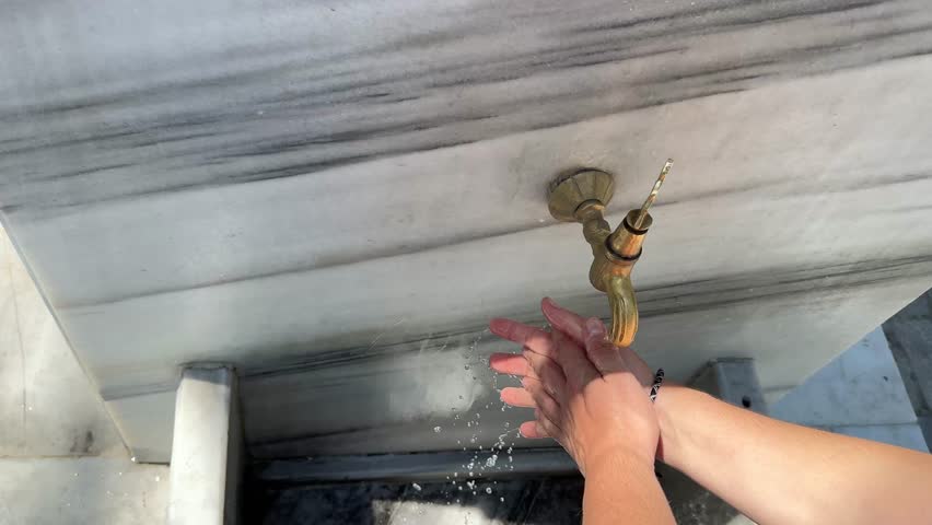 Woman washing hands and feet in ablution faucets in the Sultan Ahmed Mosque, Istanbul (Turkey)