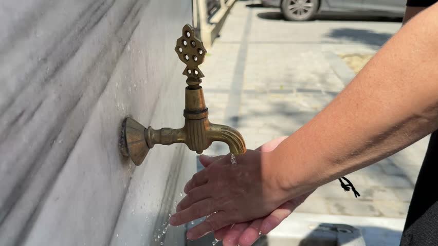 Woman washing hands and feet in ablution faucets in the Sultan Ahmed Mosque, Istanbul (Turkey)