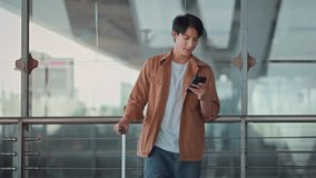 Happy Asian man using mobile smartphone standing with suitcase booking travel tickets via mobile application at airport terminal, Browse Internet, flight check in, Tourist journey trip concept - Powered by Shutterstock - Get 15% off with code: PIKWIZARD15