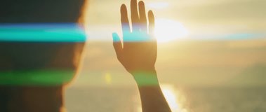 Silhouetted hand reaches toward sun over sea horizon in summer sunset scene - Powered by Shutterstock - Get 15% off with code: PIKWIZARD15