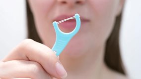 Young woman brushing teeth with disposable dental floss close-up against the background of white tiles in the bathroom. - Powered by Shutterstock - Get 15% off with code: PIKWIZARD15