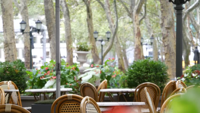 New York City, Manhattan Midtown Bryant Park with Public library, 42 street and 5th Fifth 5 avenue corner, United States. NYC landmark in USA. Outdoor autumn or summer cafe, restaurant chair and trees