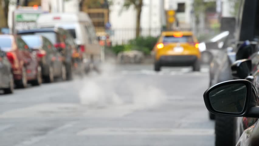 Hot smoke from manhole, Con Edisons Steam system in New York City, United States. Vapor from road. Beaver Street, NYC Downtown Financial District, Manhattan, USA. Urban scene. Yellow taxi, Broadway.