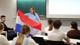 Adult female teacher showing the flag of the Netherlands to students. High quality 4k footage - Powered by Shutterstock - Get 15% off with code: PIKWIZARD15