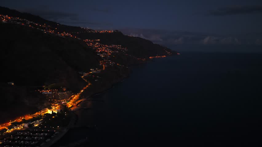 Illuminated Madeira coastline at night captured from an aerial view over Calheta. push forward