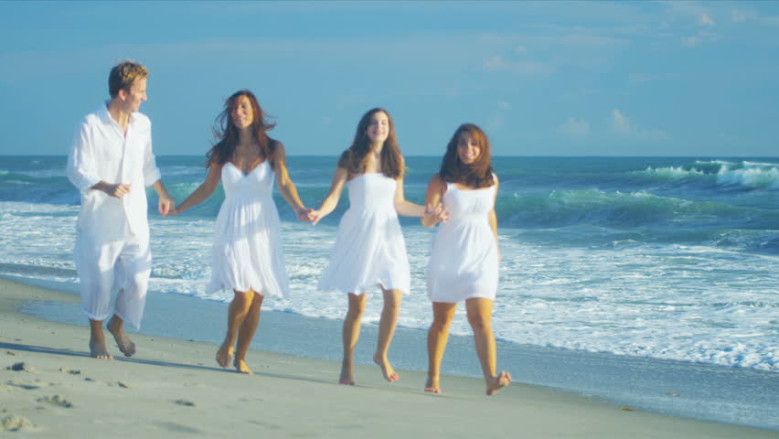 Loving Caucasian parents teenage daughters holding hands running together beach shot on RED EPIC