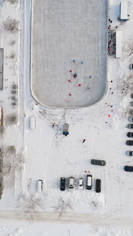 Top down aerial portrait over a ice hockey game at a outdoor rink, winter day