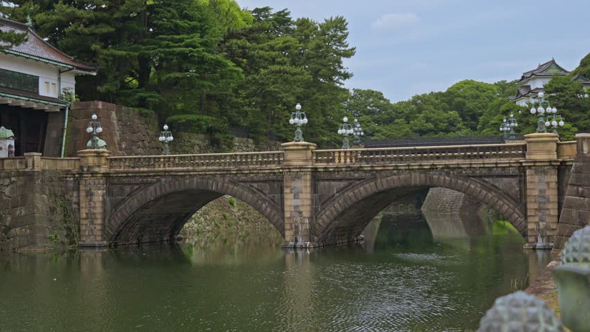 A view of the Nijubashi Bridge, a famous landmark at the Tokyo Imperial Palace, with its elegant stone arches reflected in the water.