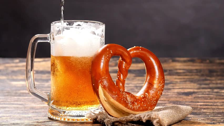 beer in glasses with salty pretzels. A glass of beer with delicious pretzels on table. Oktoberfest food menus, soft pretzels and a glass of beer.