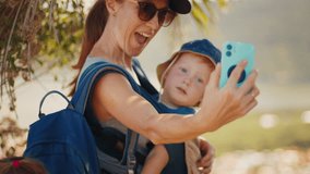 Family selfie. Woman takes selfie with kid sitting in baby carrier - Powered by Shutterstock - Get 15% off with code: PIKWIZARD15