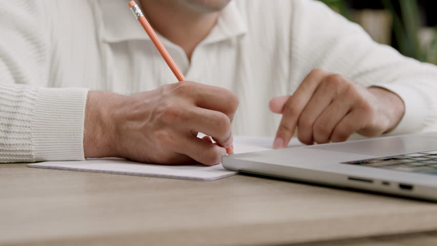 Student hand writes lecture notes with pencil near laptop - Powered by Shutterstock - Get 15% off with code: PIKWIZARD15