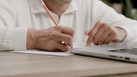 Student hand writes lecture notes with pencil near laptop - Powered by Shutterstock - Get 15% off with code: PIKWIZARD15