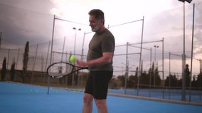 Mature male tennis player practicing powerful serve on blue tennis court, demonstrating athletic skill and concentration during evening hours under dusky sunset sky - Powered by Shutterstock - Get 15% off with code: PIKWIZARD15