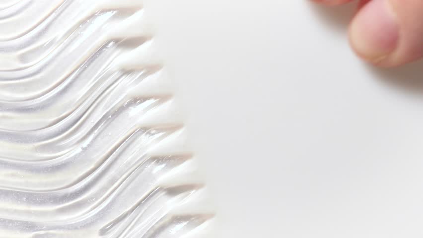 Video cut with transparent gel texture close-up. Advertising shampoo or care cosmetics. Swipe a metal and plastic spatula with a transparent gel over a white background, 4k