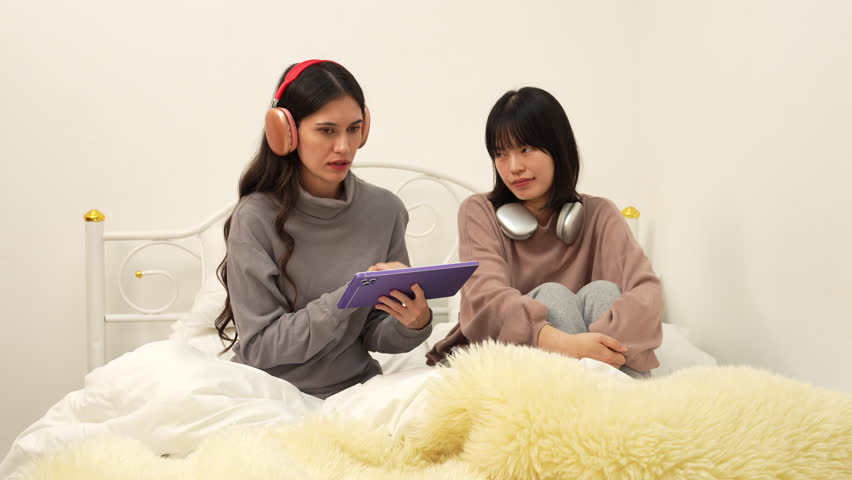 4K video Asian and European women are playing and listening to music on the bed.