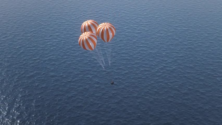 Reentry space capsule descending toward the ocean with three parachutes. Splashdown.