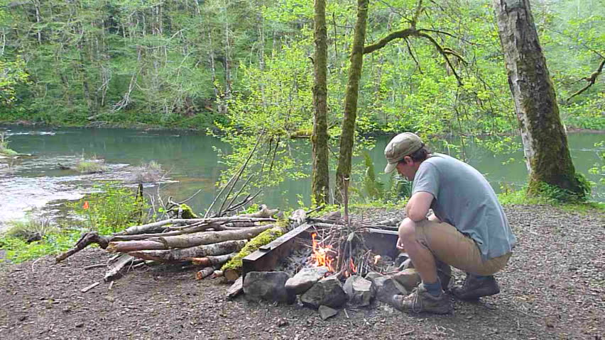 Man starts campfire at camp in the Pacific Northwest, Oregon.