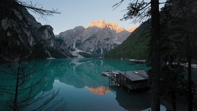 Panoramic sunrise view of Lago di Braies with still waters reflecting the Dolomites, wooden rowboats moored near the rustic boathouse in perfect alpine serenity - Powered by Shutterstock - Get 15% off with code: PIKWIZARD15