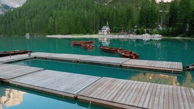 Flying low across Lago di Braies at surise. Drone video captures wooden rowboats and the historic boathouse with pristine reflections of the Dolomites - Powered by Shutterstock - Get 15% off with code: PIKWIZARD15