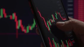 Close-up of hand interacting with stock market candlestick chart on a smartphone, indicating trading, investing, or financial analysis.  - Powered by Shutterstock - Get 15% off with code: PIKWIZARD15