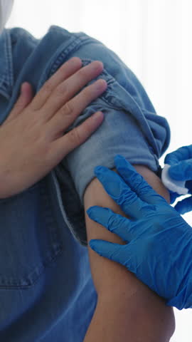 Vertical Screen : Young Asia lady nurse giving flu antivirus vaccine shot to senior male patient wear face mask protection from virus disease at health clinic or hospital office. Vaccination concept.