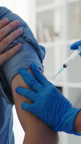 Vertical Screen : Young Asia lady nurse giving flu antivirus vaccine shot to senior male patient wear face mask protection from virus disease at health clinic or hospital office. Vaccination concept.