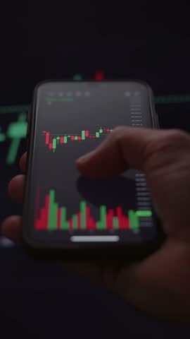 Close up, trader using a mobile trading platform application on smartphone, analyzing candlestick chart and financial graphs for stock or crypto investments.