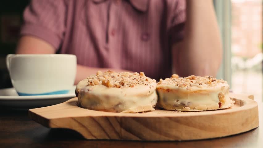 Close-up of a girl sits in cafe on table with coffee and Traditional Argentina dessert Alfajores. High quality 4k footage