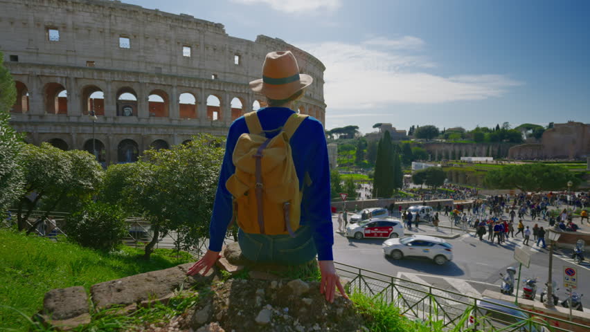 A girl tourist in a hat and with a backpack looks at the Colosseum in Rome on a sunny day - Powered by Shutterstock - Get 15% off with code: PIKWIZARD15