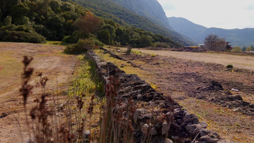 Establihsing reveal of Phocian Wall ruins in Thermopylae, Greece with mountains and dry brush landscape