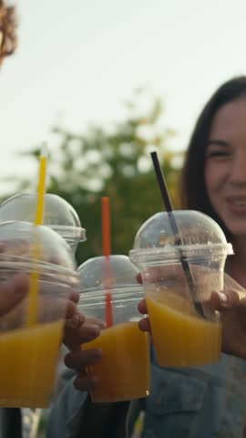 Celebrating togetherness, a lively group raises their cups filled with golden orange beverages, soaking in joyful moments in the warm sunlight
