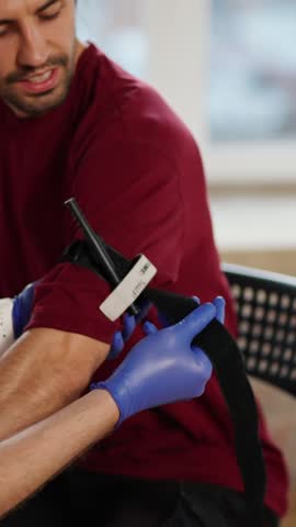 A skilled professional offers personalized assistance to a patient in a modern rehabilitation clinic, focusing on arm injury recovery with precision and care