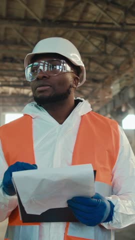 Man wearing protective gear surveys a large construction site in an urban area, showcasing his attention to detail and commitment to safety practices