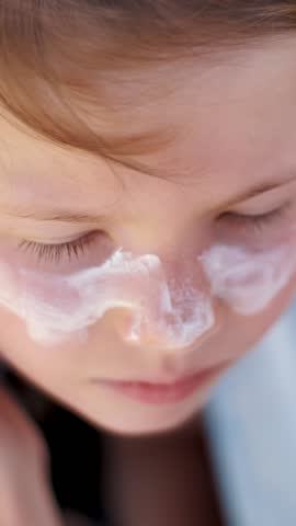 Close-up, the child, girls, severe sunburn on the face. Mom smears places of burns abundantly with a special cream. Mother applying sun protection cream to her daughter face