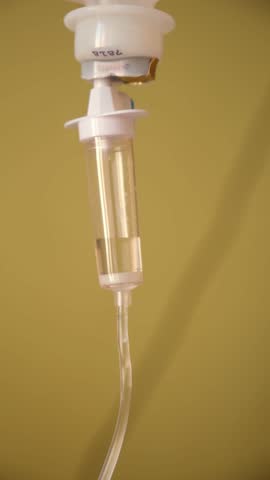 Saline solution dripping through intravenous drip in hospital room