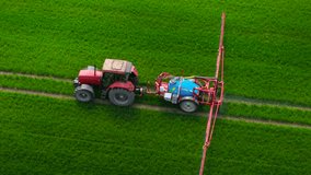 Tractor spraying nitrogen fertilizer or pesticides on agricultural field with dense green crops. Farming machine treating farmland using mounted sprayer equipment. Agricultural vehicle applying crop - Powered by Shutterstock - Get 15% off with code: PIKWIZARD15