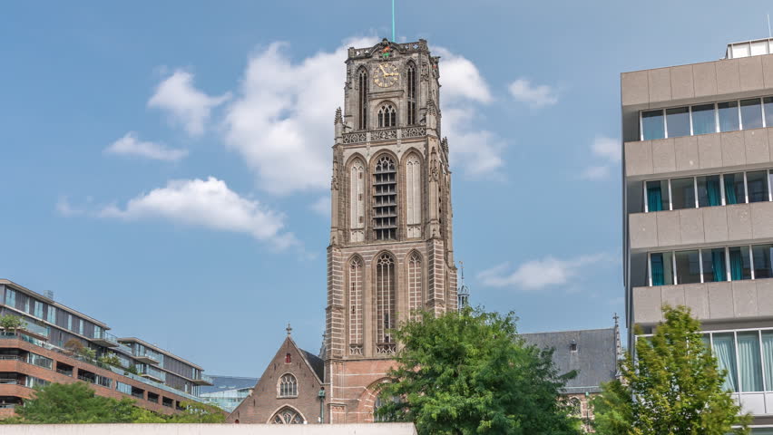 Hyperlapse of Laurenskerk (Saint Lawrence Church) on Grotekerkplein, Rotterdam. People relaxing on lawn under blue cloudy skies timelapse. Historic bell tower with clock near canal stairs. Netherlands