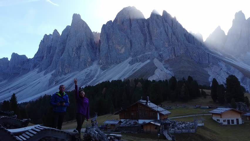 Aerial view of the picturesque peaks of Tre Cime di Lavaredo. A man and a woman admire the breathtaking views of the landscape and mountain range at sunrise in South Tyrol, Dolomites, Italy.