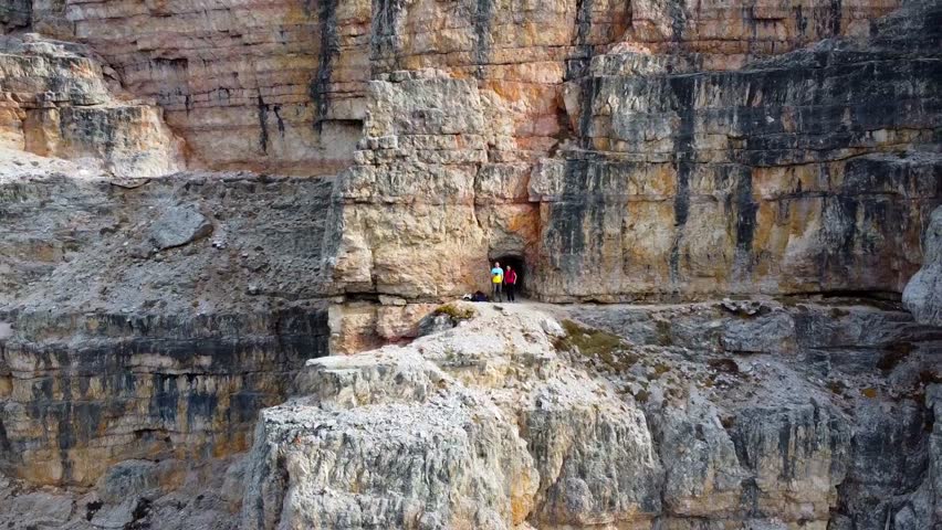 Aerial view of the beautiful Tre Cime di Lavaredo peaks. A man and a woman admire the breathtaking views of the surrounding landscape and the mountain range in South Tyrol, Dolomites, Italy.