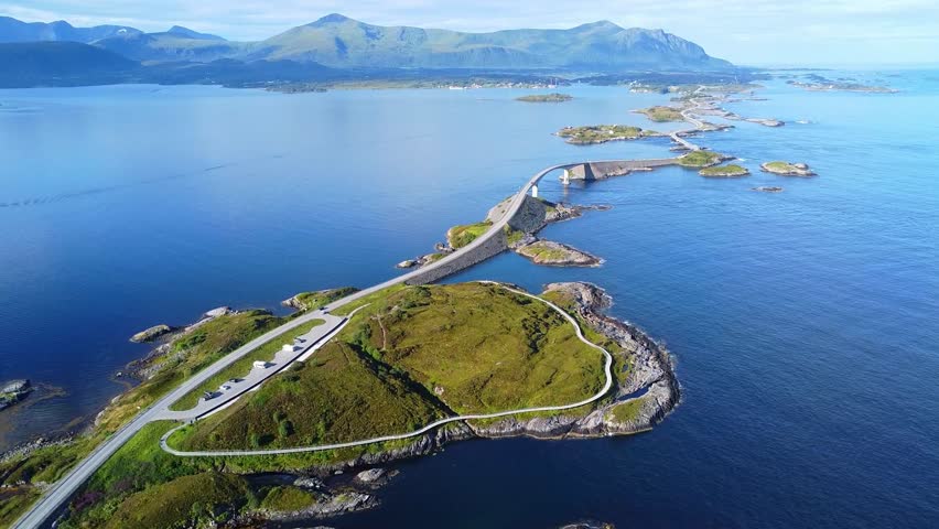 Aerial drone view of the Atlantic Ocean Road (Atlanterhavsveien) in Norway. The beauty of Norway’s coastline, where vehicles travel along a magnificent road surrounded by serene waters and green hills