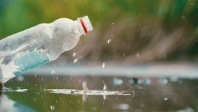 Plastic bottle falling into puddle with water splashes slow motion ground view - Powered by Shutterstock - Get 15% off with code: PIKWIZARD15
