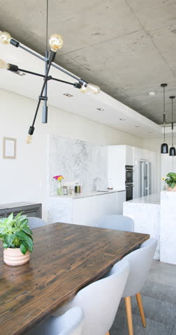 Vertical video: Modern kitchen with marble countertops and pendant lights, featuring sleek design. Interior, luxury, contemporary, minimalistic, cabinetry, appliances