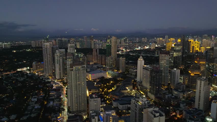 Makati with night skyline filled with illuminated buildings and bustling city life reflecting economic progress. Metro Manila, Philippines.