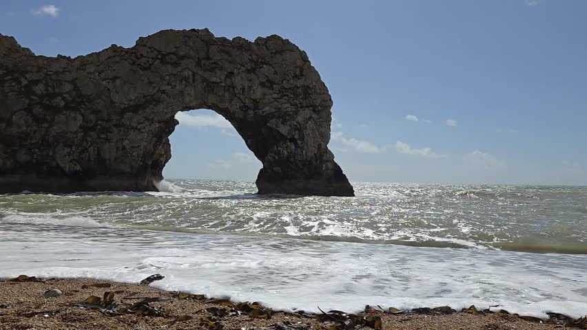Sea surf in front of iconic Durdle Door, a natural limestone arch on the Jurassic Coast near Lulworth in Dorset, England.