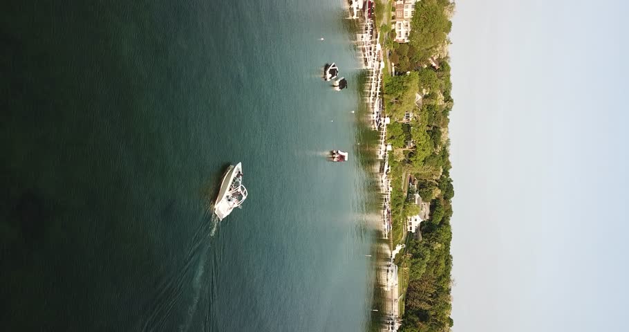 4K vertical aerial drone video of a white boat floating across the water as the camera pans from right to left in Lake Geneva, Wisconsin.