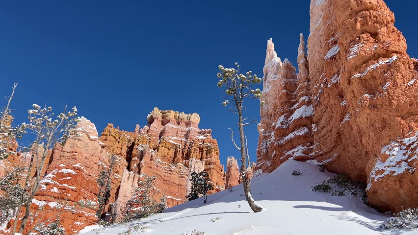 Snow-capped red rocks in Bryce Canyon, under a clear blue sky